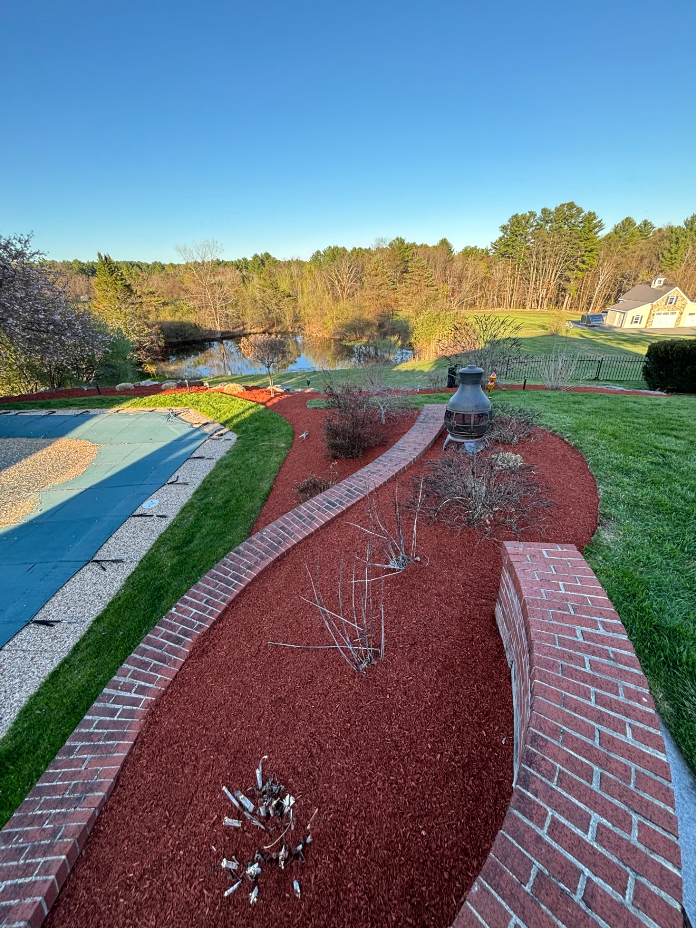Brick-edged mulch beds and walkway overlooking a pond